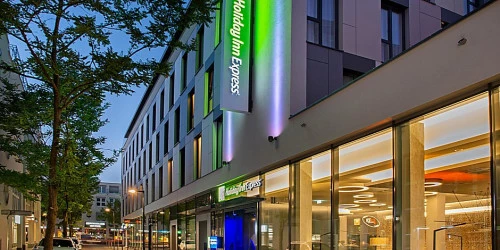 Hotelgebäude mit beleuchtetem Holiday Inn Express Schild und beleuchteten Fenstern. (KI generiert)