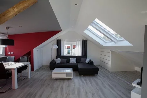 Moderne Dachgeschosswohnung mit schwarzem Sofa und weißem Esstisch (KI generiert)