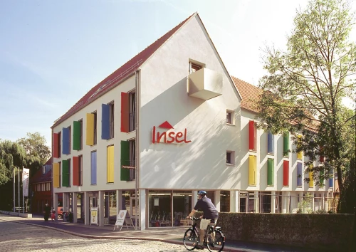 Ein Gebäude mit bunten Fensterläden und dem Schriftzug "Insel". (KI generiert)