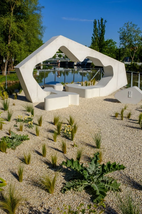 Moderne weiße Skulptur mit organischer Form und Sitzgelegenheiten in einem Garten mit Kies und Pflanzen. (KI generiert)