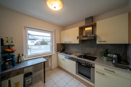 Moderne Küche mit grauer Arbeitsplatte und weißem Schrank (KI generiert)