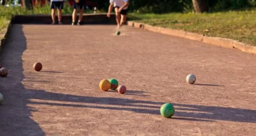 Bowlingbahn mit vier bunten Kugeln und zwei Kegeln auf der Bahn. (KI generiert)
