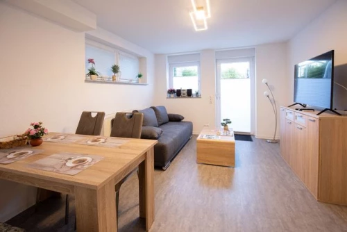 Wohnzimmer mit Esstisch, Stühlen, Sofa, TV und Pflanzen. Hell und modern eingerichtet. (KI generiert)