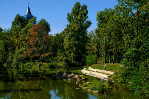 Ein Radfahrer fährt über einen Steg in einem Park mit See und Bäumen. (KI generiert)