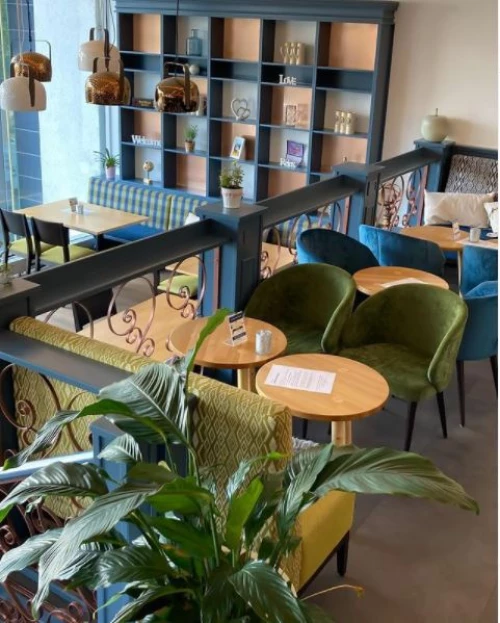 Ein gemütlicher Loungebereich mit grünen Sesseln und runden Tischen. (KI generiert)