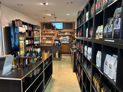 Ein Café mit Theke, Kaffeemaschine, Regalen voller Kaffeesäcke und Flaschen. (KI generiert)