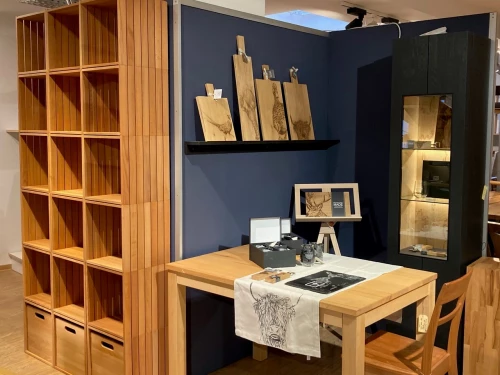 Holzmöbel mit Regalen, Tisch und Stühlen, dekoriert mit Holzschildern und Tischdecke mit Hirschkopfmuster. (KI generiert)