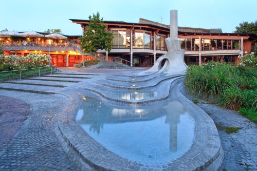 Moderne Architektur mit Brunnen und Stufen, umgeben von Pflanzen und beleuchteten Terrassen. (KI generiert)