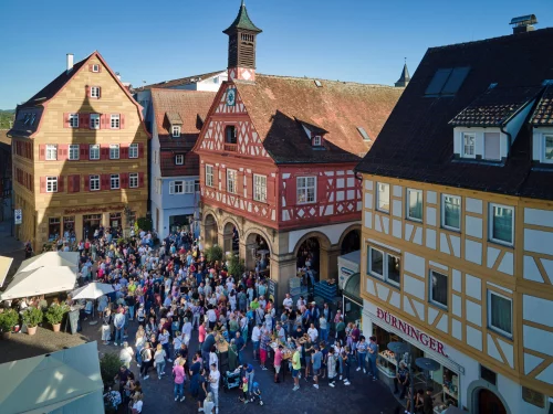Ein belebter Marktplatz in einem historischen deutschen Städtchen mit Fachwerkhäusern und vielen Besuchern. (KI generiert)